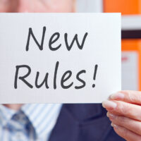 New Rules! written on notecard held up with hand New Rules! written on notecard held up with hand