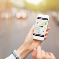 Hand holding phone with uber ridesharing app open Hand holding phone with uber ridesharing app open