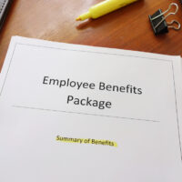 Form that reads employee benefits package on a desk with surrounding office supplies