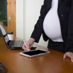 view of working pregnant worker on cellphone