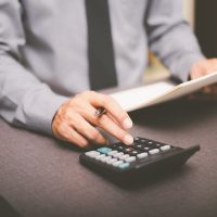 Business people use calculator to calculate documents, profit and loss statement review concept of company performance, effective tax deduction planning for individuals and companies paying tax rates Business people use calculator to calculate documents, profit and loss statement review concept of company performance, effective tax deduction planning for individuals and companies paying tax rates