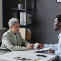 Side view portrait of mature woman with disability speaking to recruiter in job interview