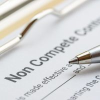 Blue pen on a non compete contract. Noncompete contract is an agreement between employee and employer, not to enter into competition in subsequence business effort. Legal concept.
