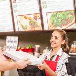 Restaurant worker serving food with smile.