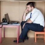 depressed businessman in a cardboard office